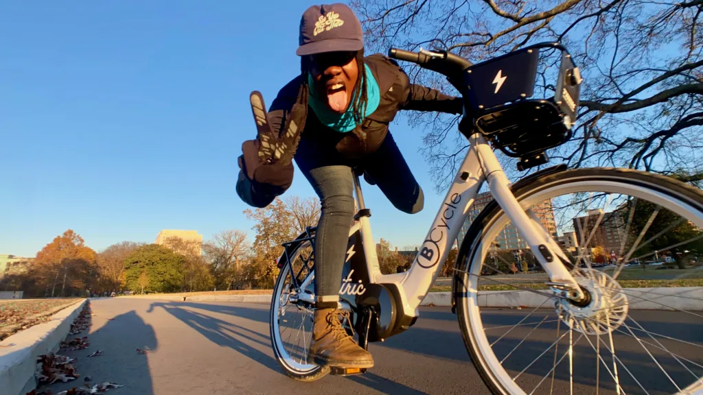 Woman giving the camera a peace sign while riding a bike share bicycle