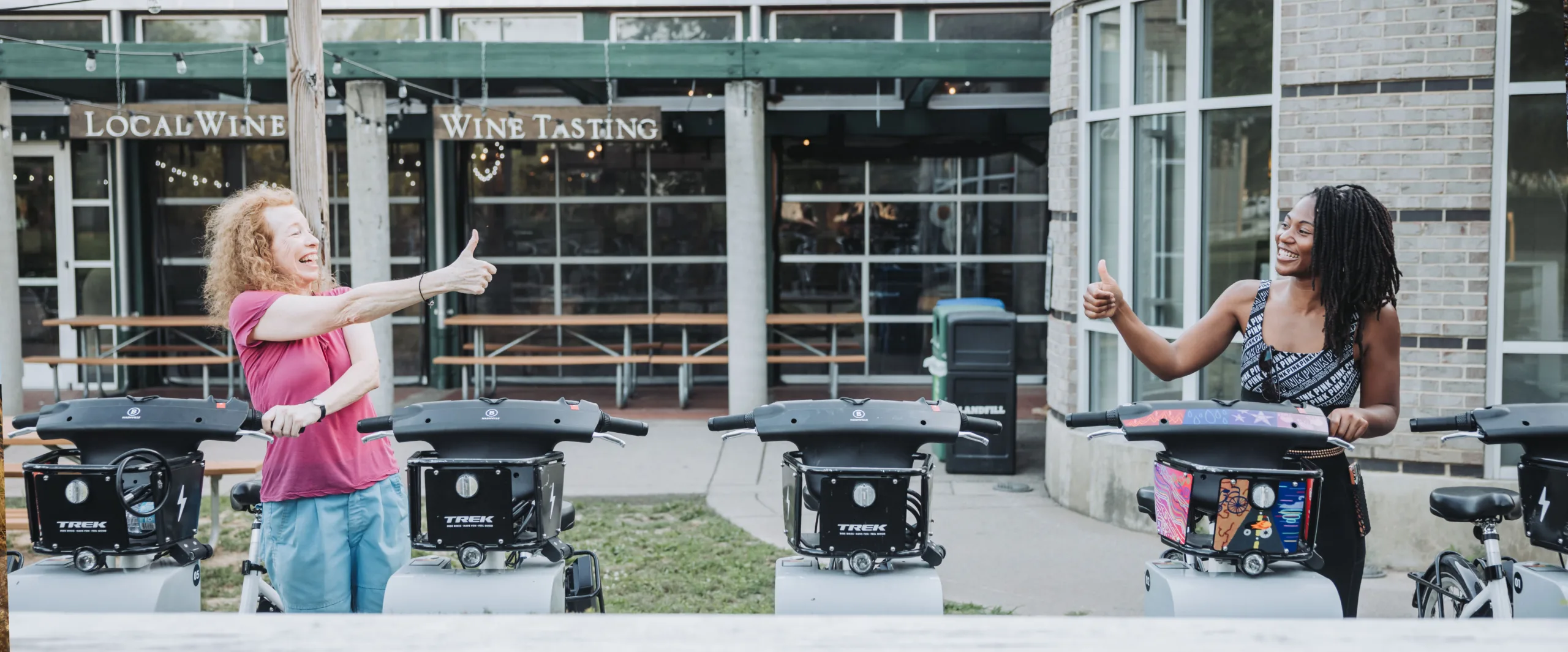 Photo of two women giving a thumbs up at a bike share docking station