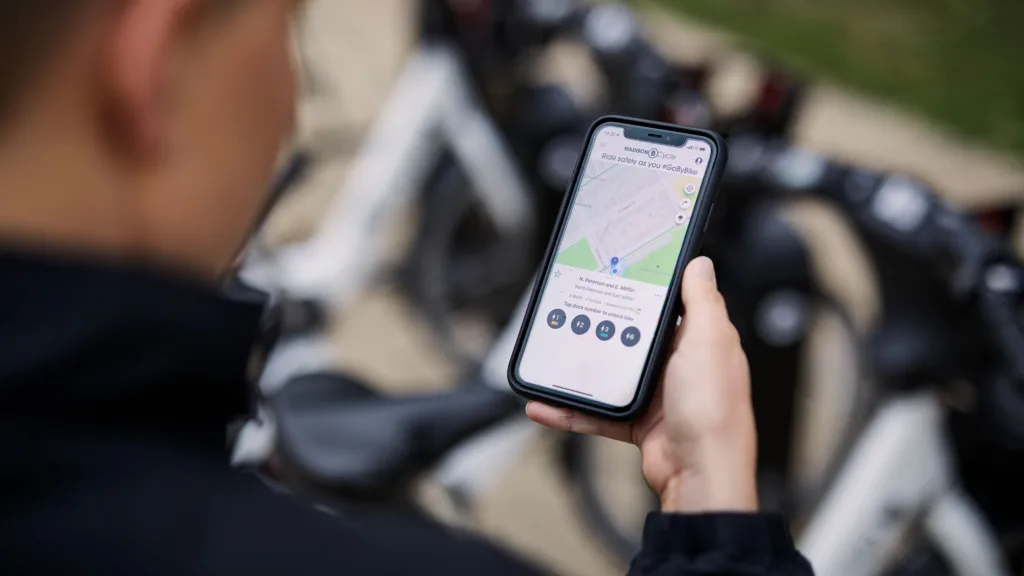 Photo of woman holding a smart phone using the BCycle bike share app